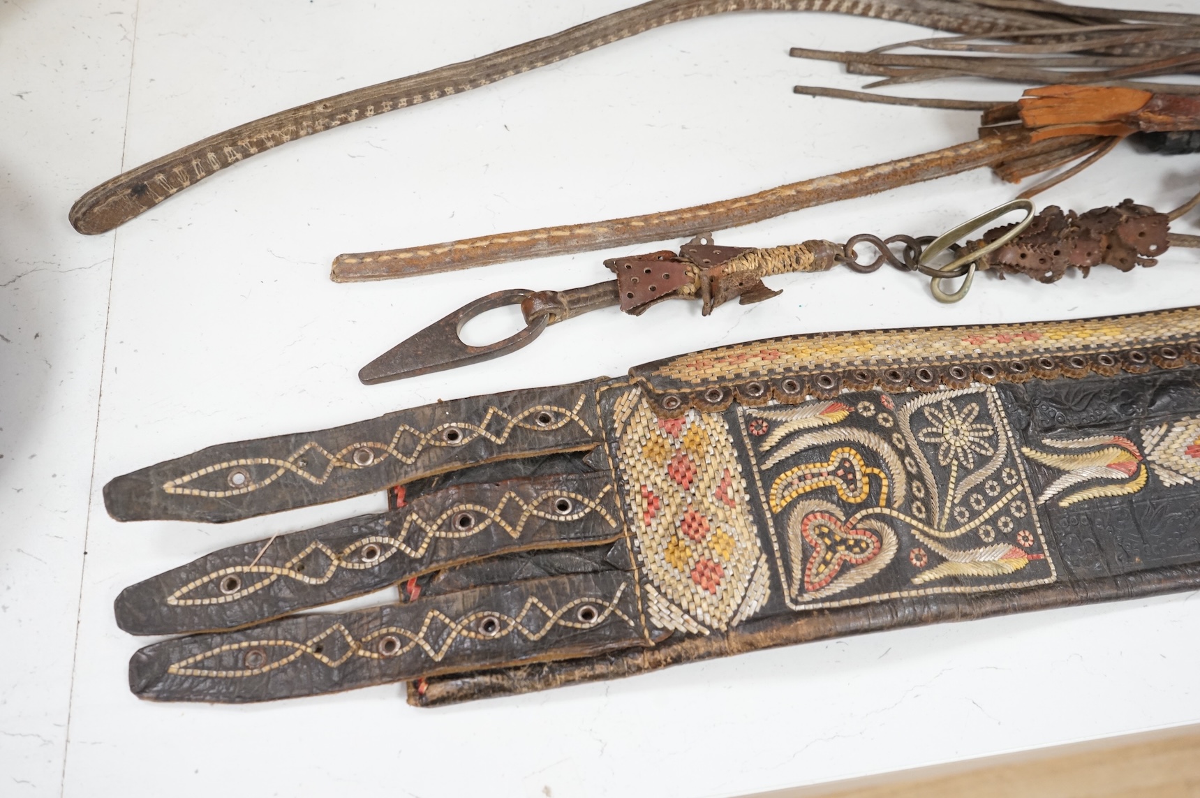 An Argentinian braided leather belt and whips, one with mother of pearl inlay